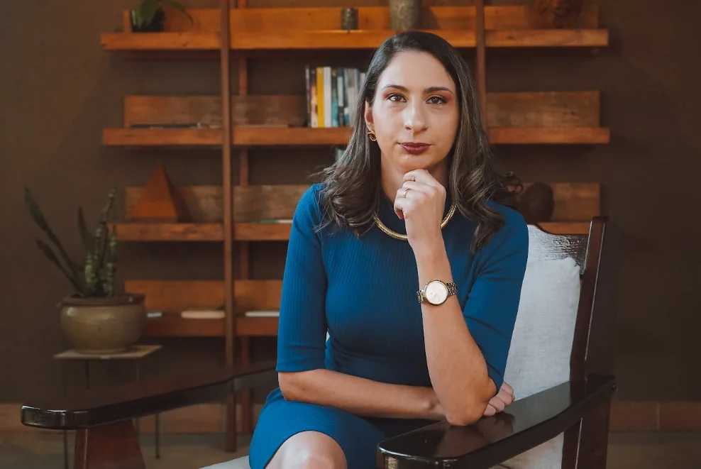 Nayara Jayme sentada em uma poltrona, em ambiente profissional acolhedor